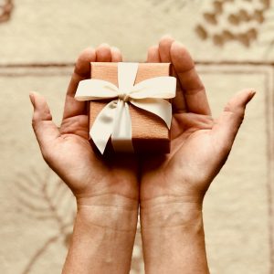 Close-up of hands holding a beautifully wrapped gift box with a ribbon, perfect for celebrations and surprises.