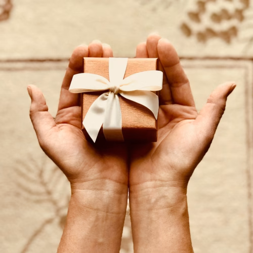 Close-up of hands holding a beautifully wrapped gift box with a ribbon, perfect for celebrations and surprises.