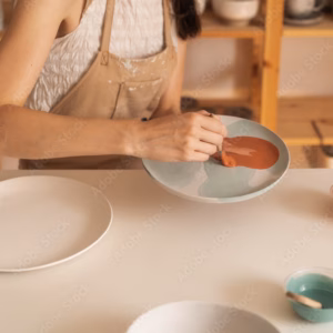 L'Arte della Smaltatura Ceramica: Tecniche e Strumenti Essenziali 3 Anonymous Woman Applying Glaze On The Plate In The Pottery Workshop