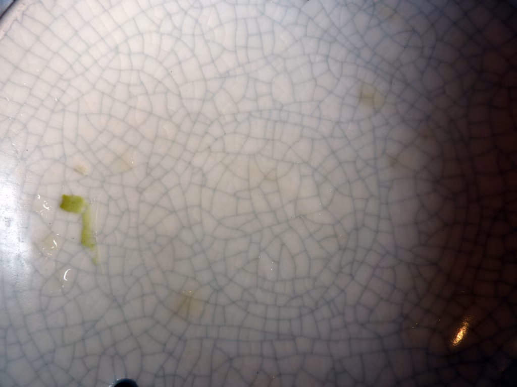 Difetti di Smaltatura della Ceramica: Come Riconoscere e Risolvere Cavillatura, Sfogliamento, Puntinature e Buchi di Spillo 2 Dettaglio macro di superficie ceramica con ragnatela di cavillatura e microfessurazioni dello smalto vetroso