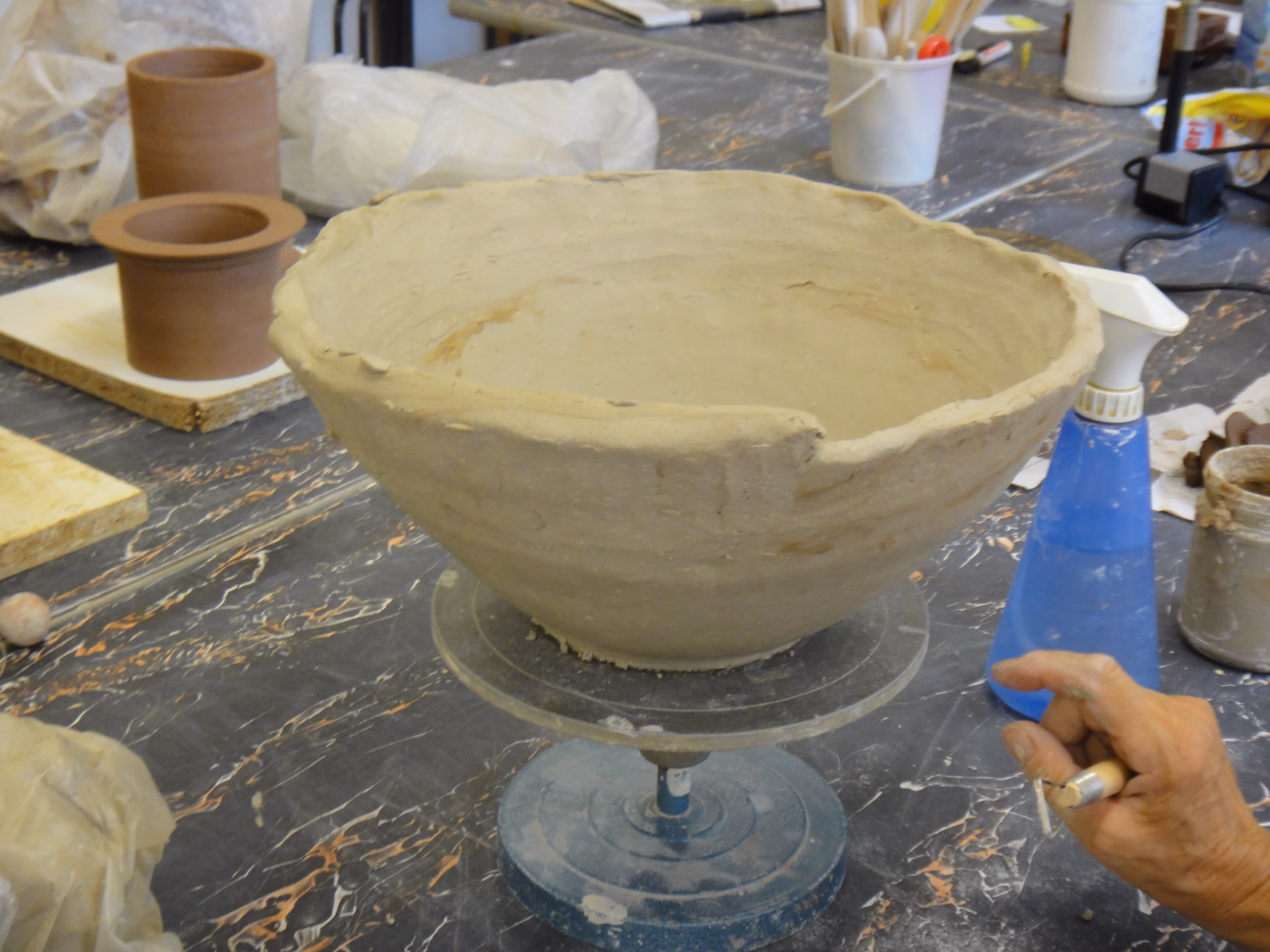 Mani di ceramista al lavoro su cordoli e colombini di argilla per la costruzione di manufatti ceramici